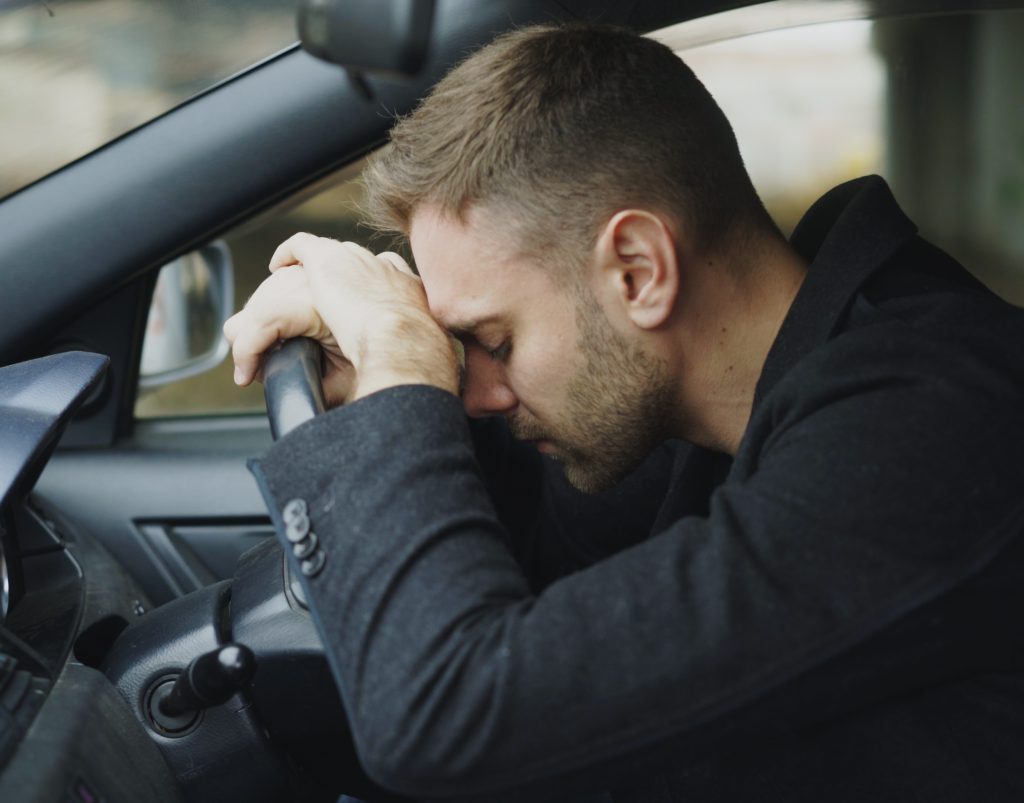 Young depresses man sitting inside car very upset and stressed 